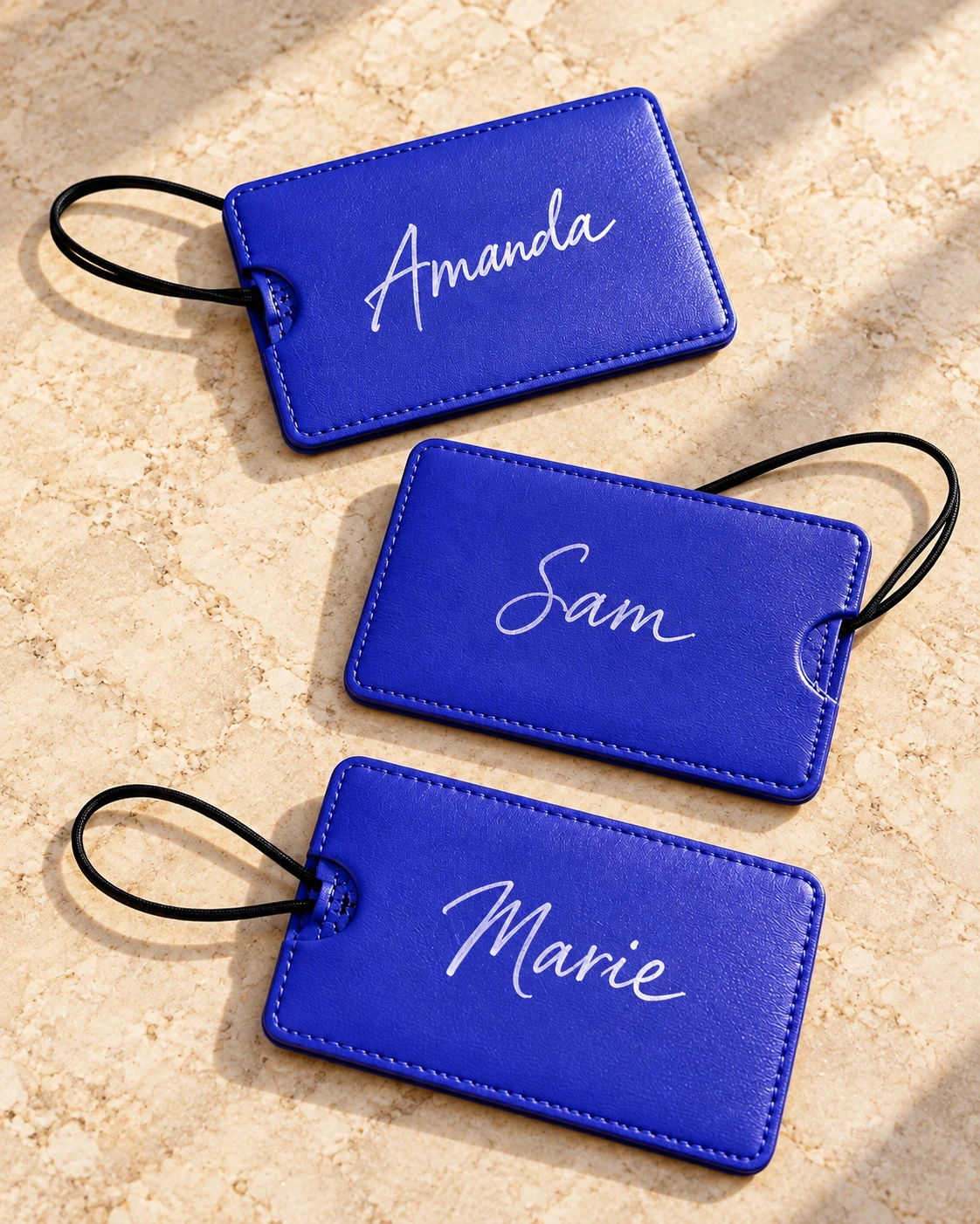 Three blue luggage tags personalized with white calligraphy