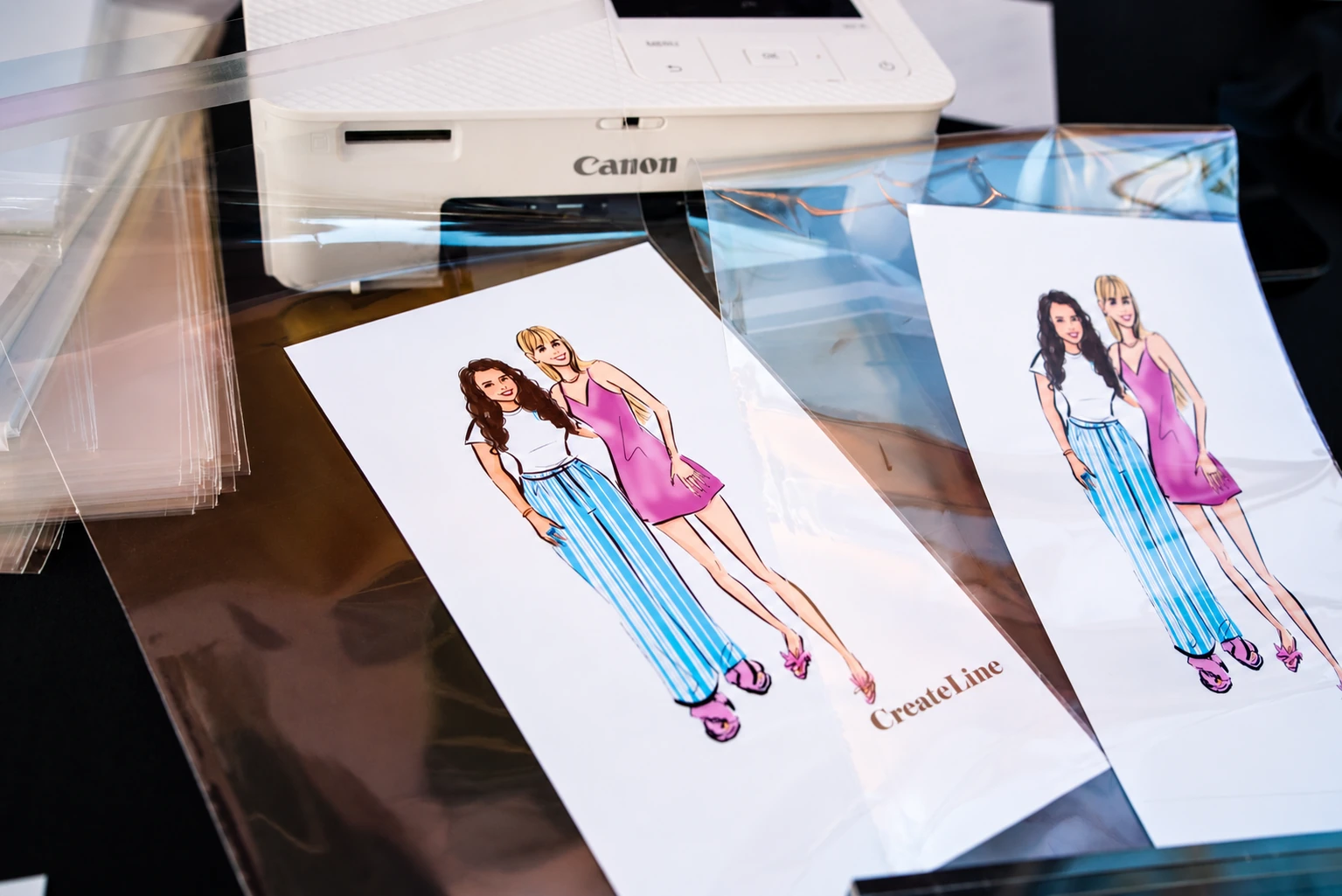 Event printer beside completed digital fashion portrait prints and protective sleeves