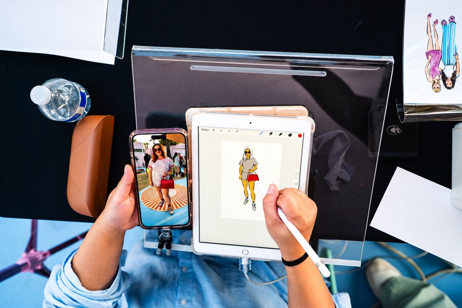 Artist drawing a digital fashion sketch on a tablet using a guest photo as reference