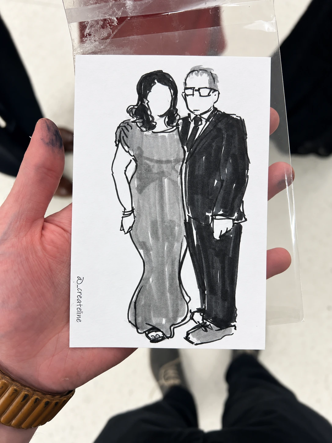 Black-and-white fashion sketch of a couple, held in a clear sleeve