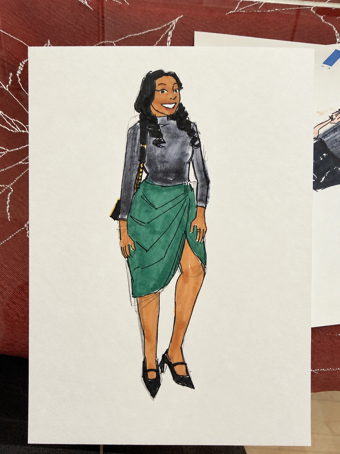 Color fashion sketch on paper of a woman in a gray top and green draped skirt