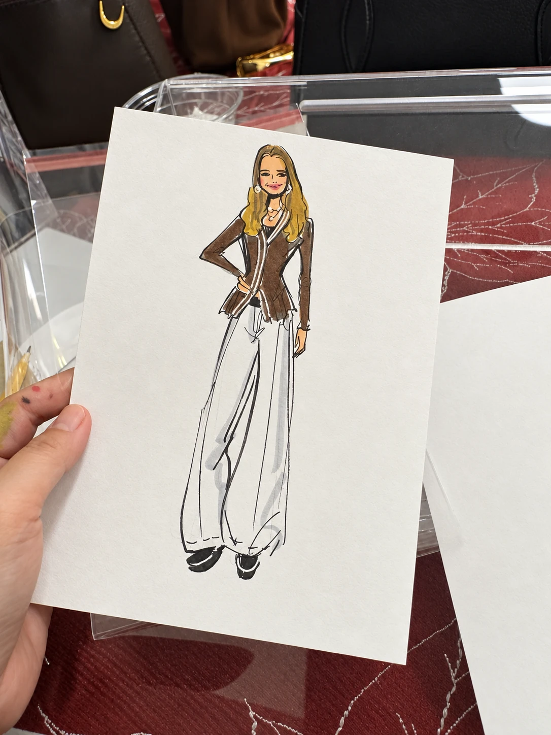 Traditional fashion sketch in a brown jacket and wide light trousers, with card branding removed