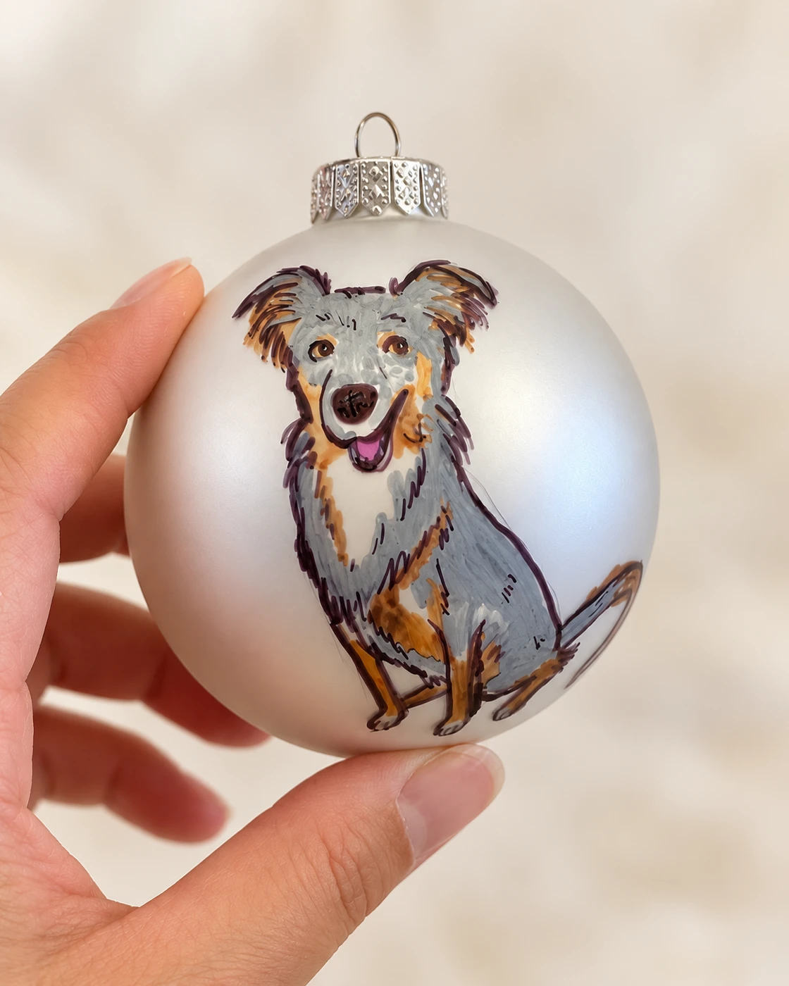 Hand holding a frosted ornament painted with a dog portrait