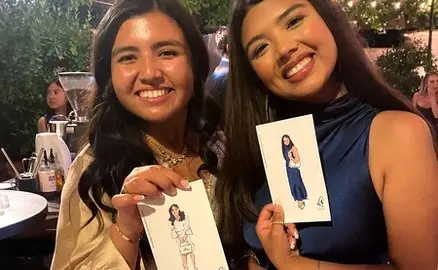 Two guests holding their printed digital fashion sketches