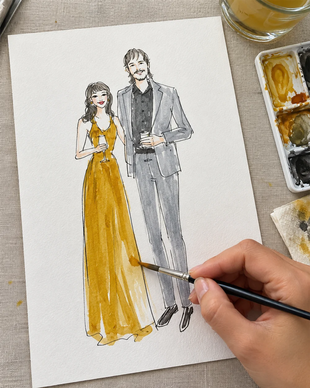 Artist adding watercolor to a couple’s fashion sketch