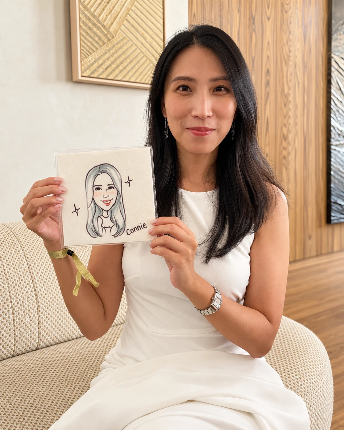 Guest in white holding her hand-drawn cocktail napkin portrait