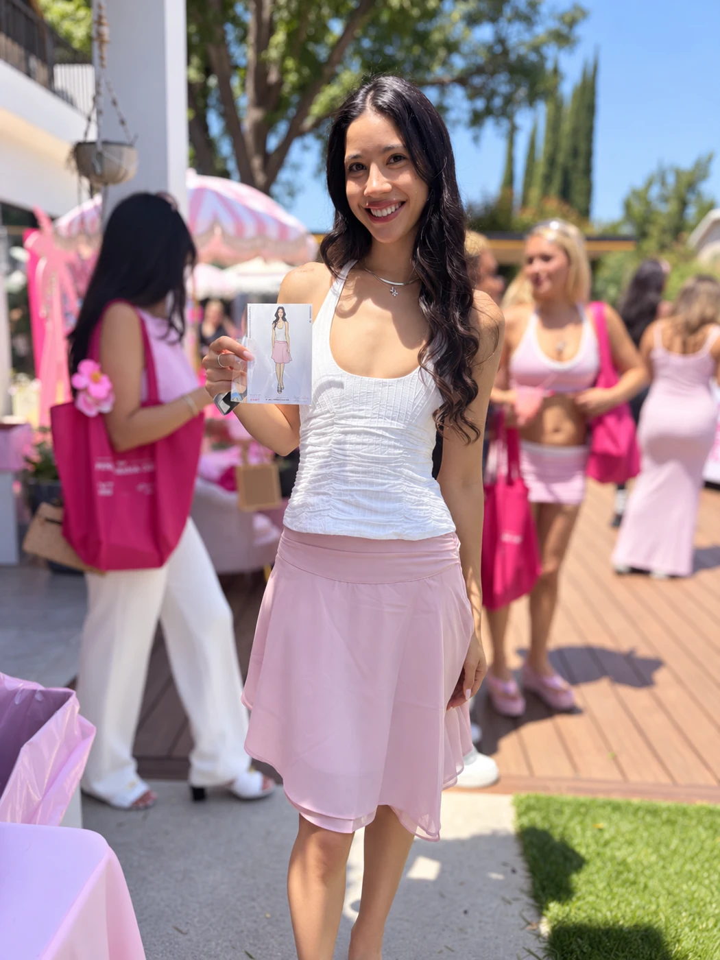 Guest in a lilac skirt showing her fashion sketch at an outdoor event