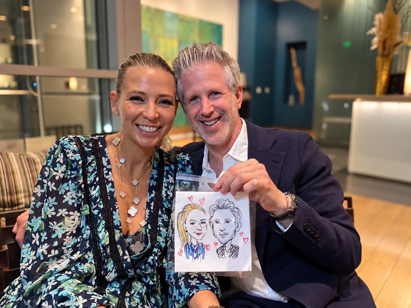 Smiling couple holding their hand-drawn napkin portrait in a protective sleeve