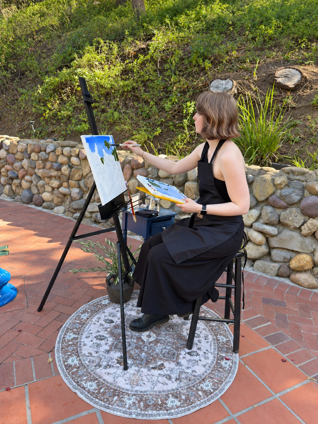 Artist adding details to a live painting in a sunny courtyard
